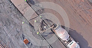 At the construction site, a concrete mix truck is pouring cement during the construction of a sidewalk for workers