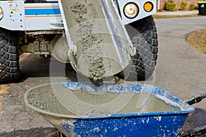 During a construction site, a concrete mixer truck is pouring wet cement into a wheelbarrow