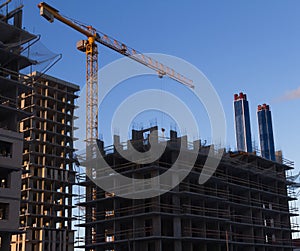 Construction site the construction of a multistory building, the installation of the metal panels crane in yellow on a background