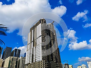 Construction site, crane and big building under construction against blue cloudy sky