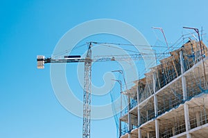 Construction site with crane over blue sky background. Construction of modern apartment house, new skyscraper building