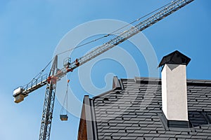 Construction Site - Crane and a Roof of a House on Clear Blue Sky