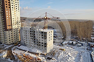 Construction site with crane and under construction high-rise apartment house.