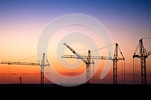 Construction site with cranes against a sunset sky