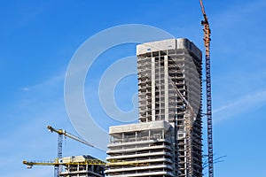 A construction site with cranes and a blue sky backdrop
