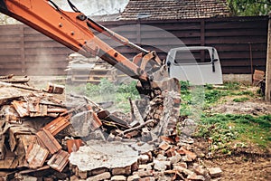 construction site details with excavator using scoop for demolishing and destroying old house photo