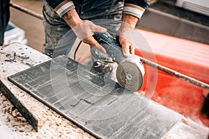 Construction site details - industrial tool, worker with angle grinder cutting marble and granite stone