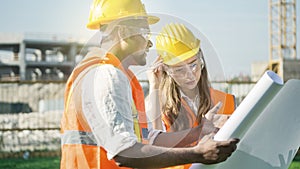 Construction site engineers and architects with safety helmet with building background with the plan or blueprint of the project