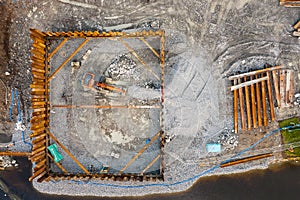 Construction site with heavy machinery by a river. Aerial top down view. Building industry. Development area for commercial or