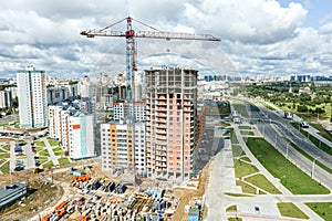 Construction site with high-rise apartment building and cranes on cloudy sky background. aerial view