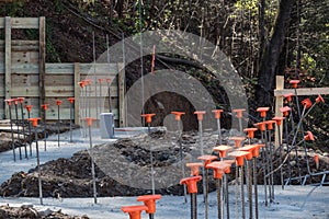 Construction site on hillside with footings poured and rebar with orange safety caps