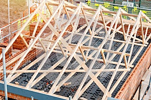 Construction site with house being built from brick and timber, featuring brickwork, roof trusses and scaffolding. House roof