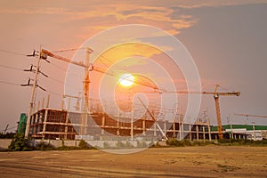 A construction site including several cranes working on a building, Boom crane on the construction of a high-rise and scaffolding