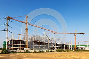 A construction site including several cranes working on a building, Boom crane on the construction of a high-rise and scaffolding