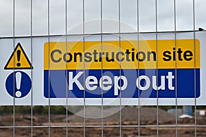 Construction site keep out sign on metal fence with blurred building site in background