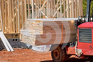 In a construction site, a lift manipulator unloads wooden building materials that have been delivered