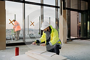 Construction site manager using digital tablet to inspect building progress.