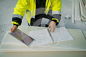 Construction site manager using digital tablet to inspect building progress.