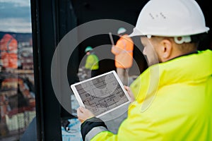 Construction site manager using digital tablet to inspect building progress.