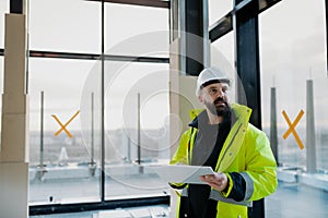 Construction site manager using digital tablet to inspect building progress.