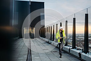 Construction site manager using digital tablet to inspect building progress.