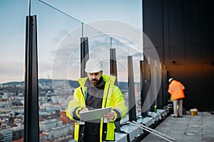 Construction site manager using digital tablet to inspect building progress.