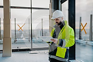 Construction site manager using digital tablet to inspect building progress.