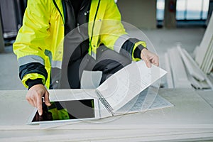 Construction site manager using digital tablet to inspect building progress.