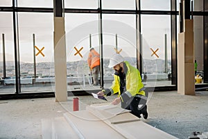Construction site manager using digital tablet to inspect building progress.