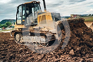 construction site with mini bulldozer pushing earth and leveling ground