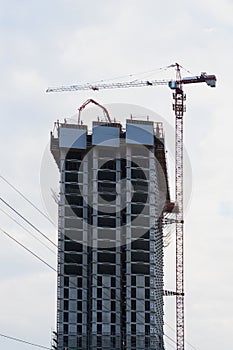 Construction site of modern high-rise building. Lift tower crane and new residential building under construction against