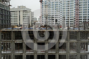 Construction site of a multi-storey building. Winter time. Several workers work on the construction site