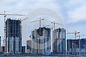 Construction site of multi-storey houses and building cranes