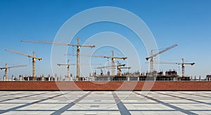 Construction Site with Multiple Tower Cranes and Building Frameworks Under a Clear Blue Sky development