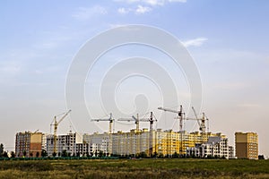 Construction site of a new apartment high building with tower cranes against blue sky. Residential area development. Real estate p