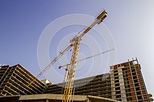 Construction site. New building. Yellow tower crane against blue sky.