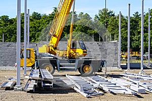 Construction site of a new industrial building with vertical steel columns and a telescopic crane