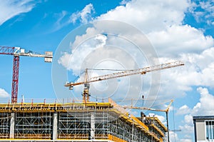 Construction site of new mall or shopping center in the city with cranes machinery, scaffolding, concrete with steel reinforcement