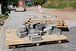 Construction site for a new road for cars. Laying paving blocks, new wells along the road.