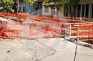 Construction site orange safety net fence as barrier over the trench on the street excavation for new district heating pipeline re