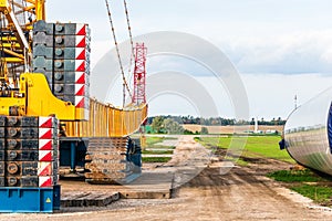 Construction site prepared for the assembly of a wind farm. Visible car crane, yellow crane and a folded gondola, mast the rotor