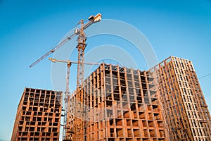 Construction site with reinforced concrete and brick buildings and cranes.