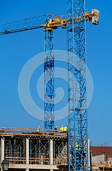 Construction site with scaffolding, crane and workers, building frame under construction