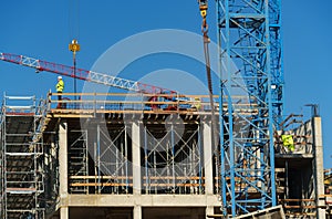 Construction site with scaffolding, crane and workers, building frame under construction