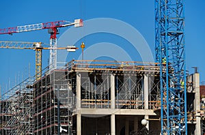 Construction site with scaffolding, crane and workers, building frame under construction