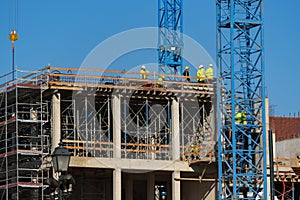 Construction site with scaffolding, crane and workers, building frame under construction