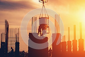 Construction site with scaffolds and workers silhouettes at sunset sky background. Modern industry development concept