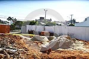 Construction site with sidings and earth being removed for general renovation of house in urban area in foreground sand for constr