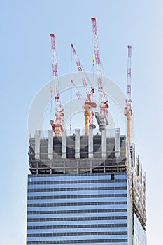 construction site of a skyscraper with cranes on the top