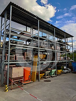 Construction site stacked storage shelves with pallets, cement mixers and raw materials. Exterior shot, sunny blue sky, no people.